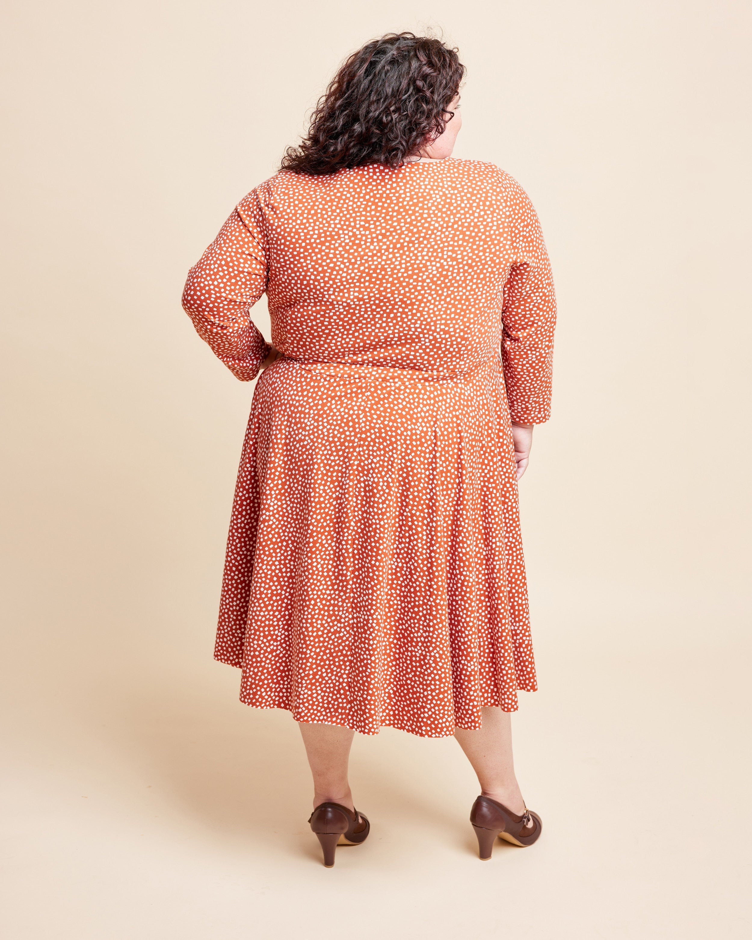 Woman wearing a patterned dress on a beige background. This is the Grafton Dress, Top & Skirt sewing pattern from Cashmerette.