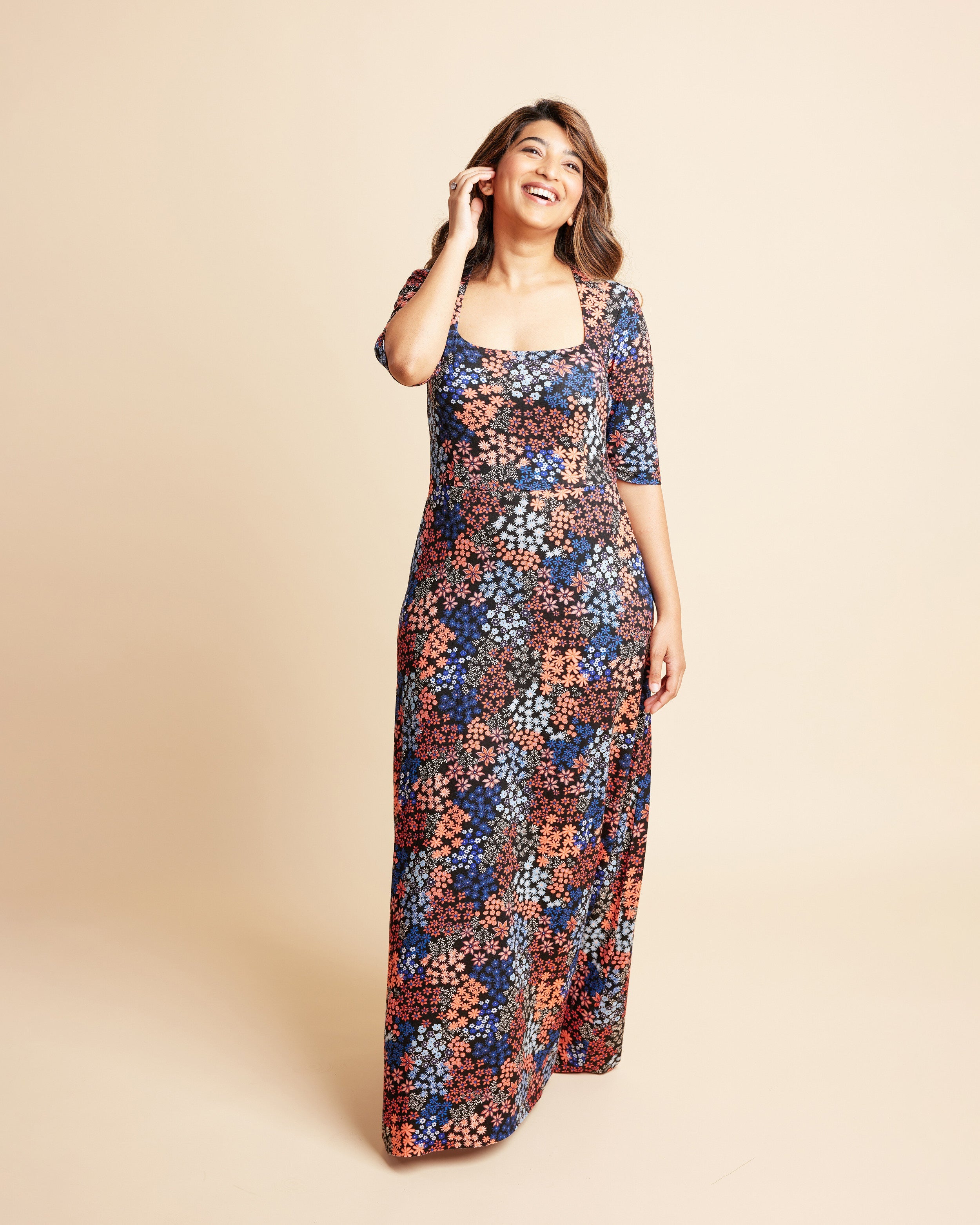 Woman wearing a floral dress on a beige background. This is the Grafton Dress, Top & Skirt sewing pattern from Cashmrette.