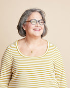 Woman wearing a yellow and white striped shirt against a beige background. This is the Grafton Dress, Top & Skirt sewing pattern from Cashmerette.