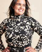 Woman wearing a black and white floral patterned top against a beige background. This is the Grafton Dress, Top & Skirt sewing pattern from Cashmrette.