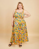 Woman wearing a yellow floral dress on a beige background. This is the Holyoke Maxi Dress & Skirt sewing pattern from Cashmerette.