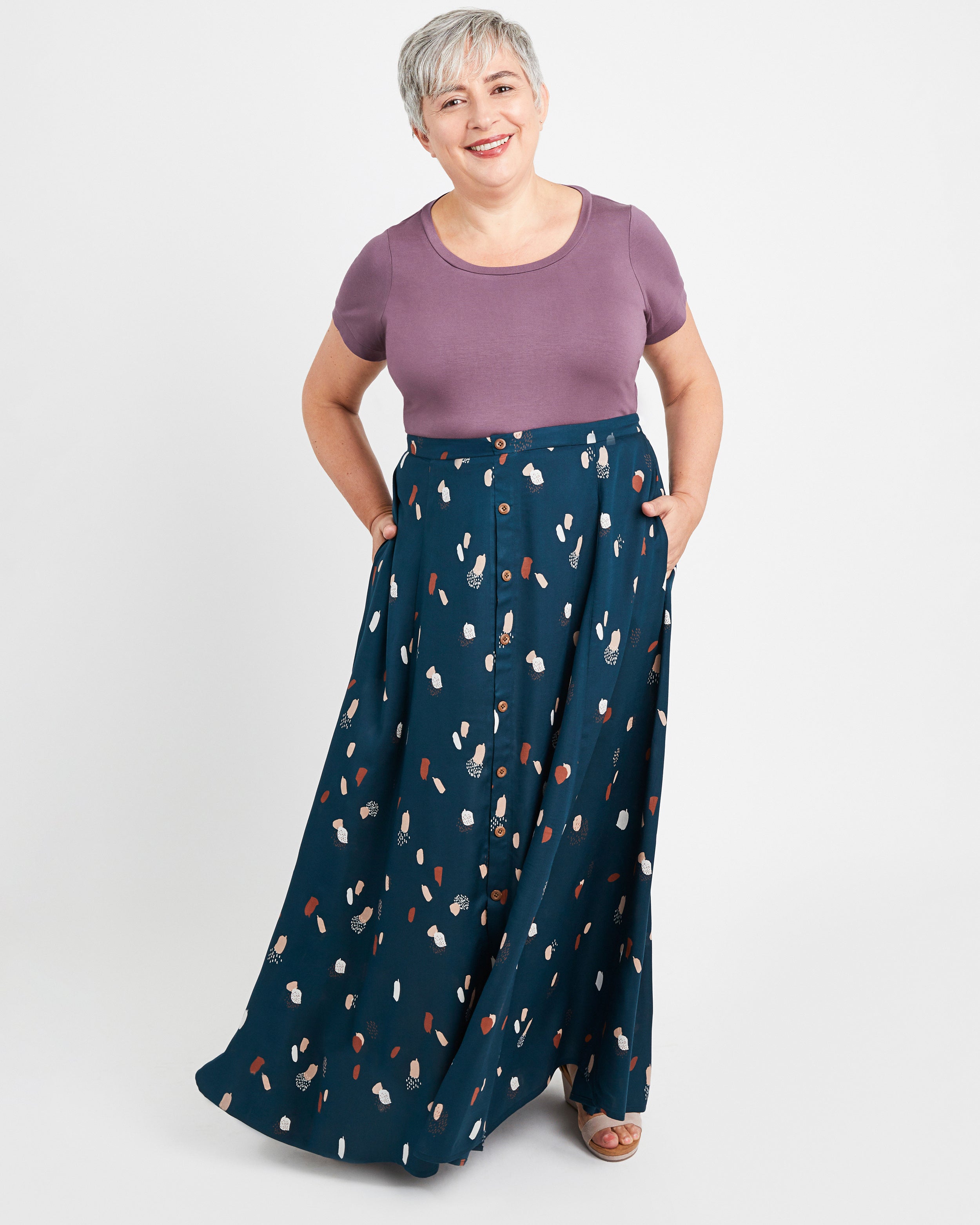 Woman wearing a purple top and navy patterned pants on a white background. This is the Holyoke Maxi Dress & Skirt sewing pattern from Cashmerette.