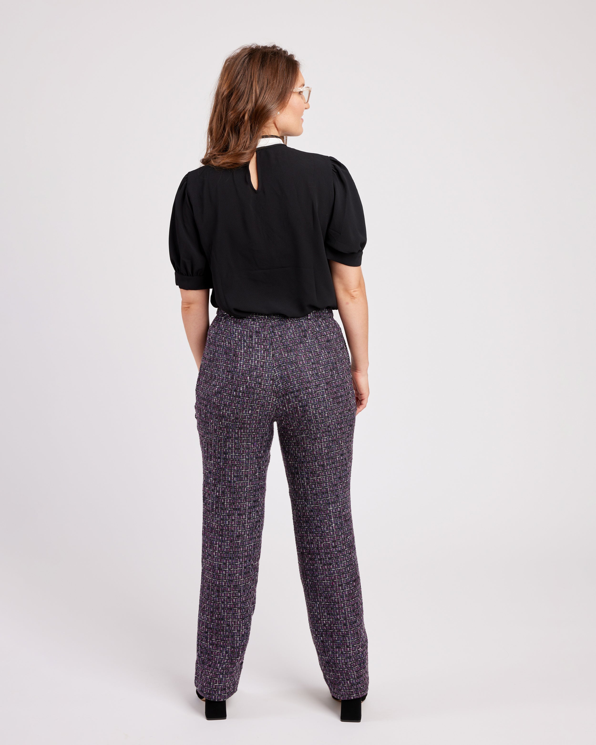Woman wearing a black blouse and patterned pants on a white background. These pants are the Meriam Trousers sewing pattern from Cashmerette.