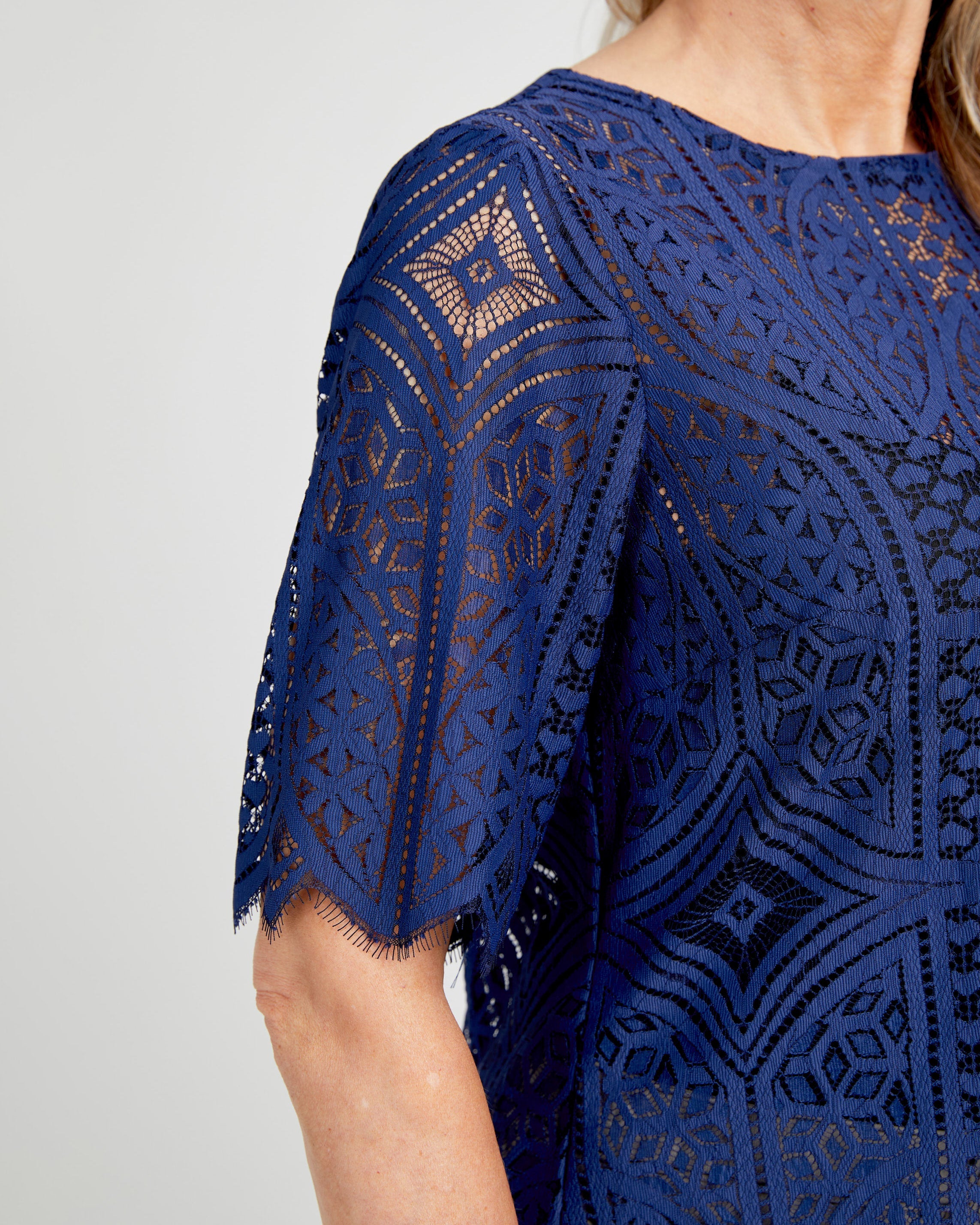Navy blue lace dress with geometric pattern on a plain background. This top is the Montrose Top sewing pattern from Cashmerette.