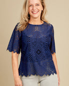 Woman wearing a blue lace top against a beige background. This top is the Montrose Top sewing pattern from Cashmerette.