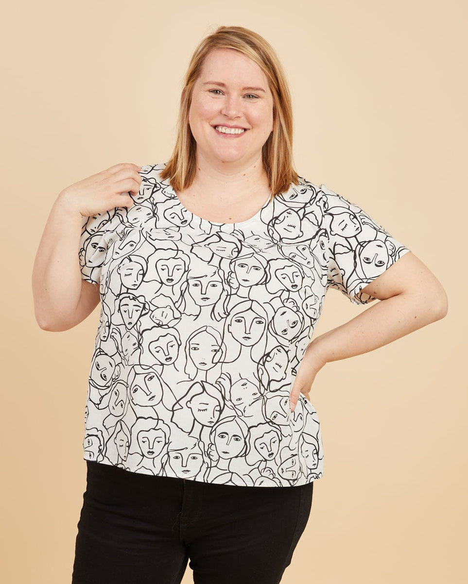 Woman wearing a black and white patterned top and black pants on a beige background. This is the Montrose Top sewing pattern from Cashmerette.